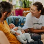 Une doula qui discute avec un jeune papa lors d'une visite postnatale à domicile